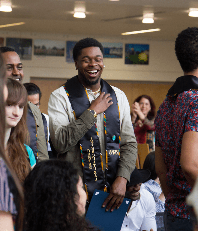 一名学生在毕业典礼上微笑，自豪地代表着跨文化中心
